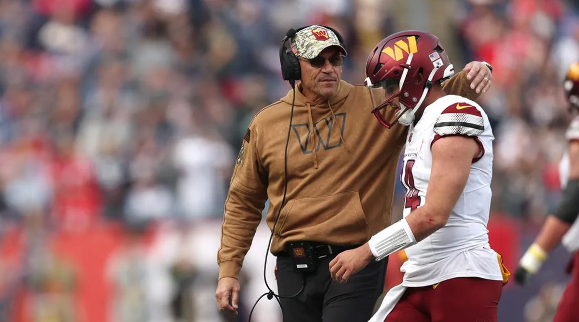 Washington Commanders quarterback Sam Howell and head coach Ron Rivera talking on the sidelines